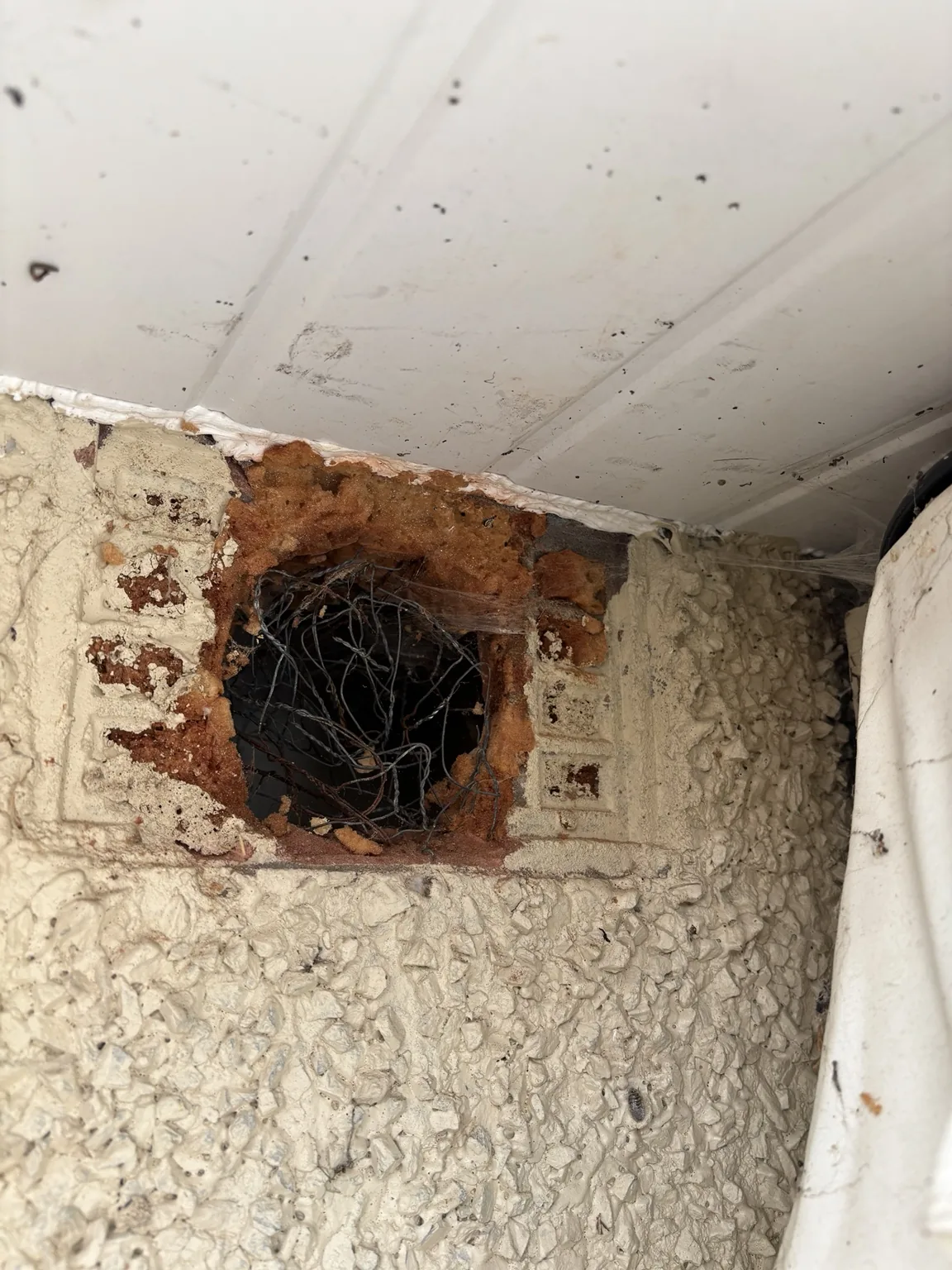 Damaged former external wall vent with an incomplete cover and exposed opening