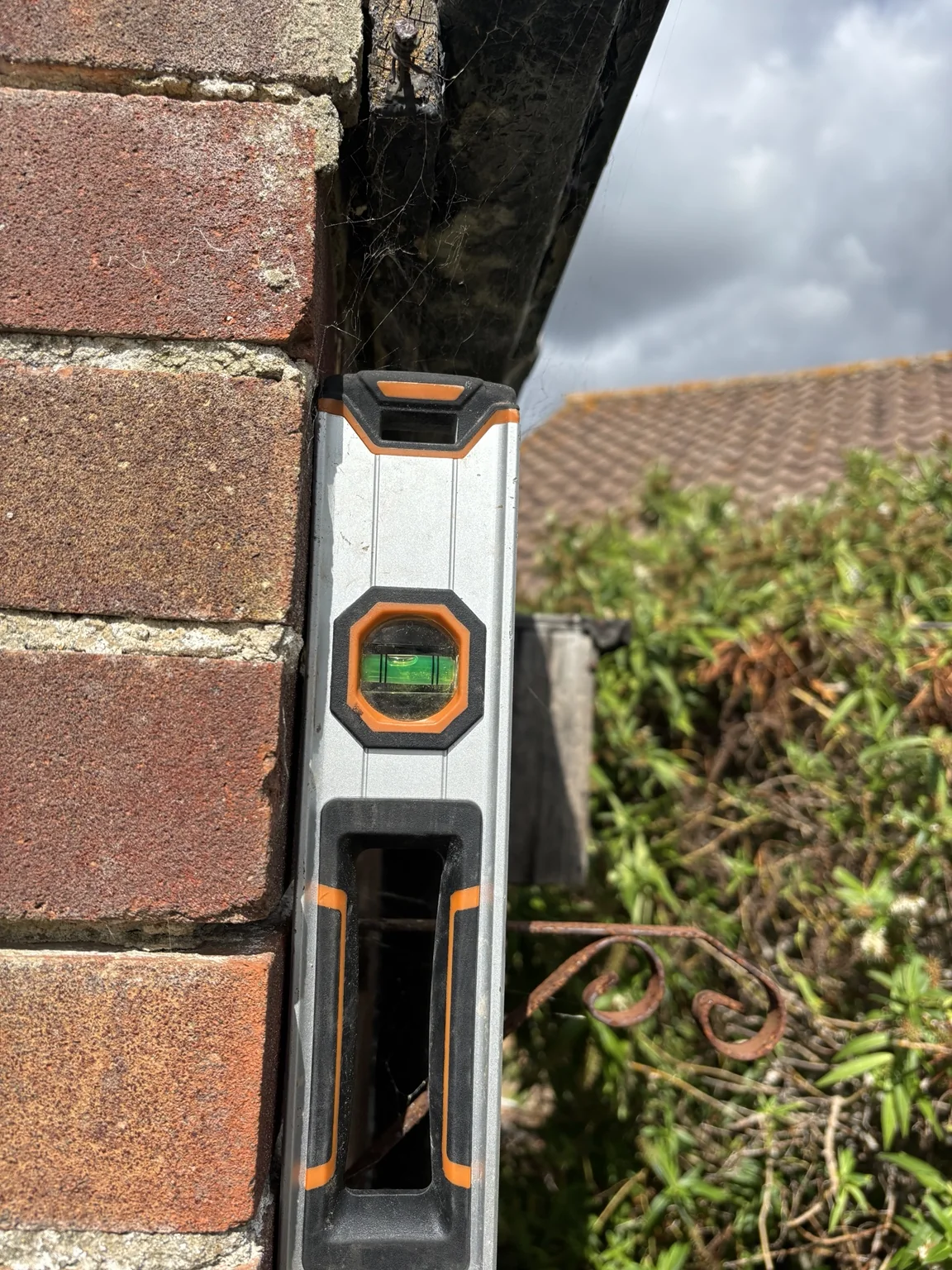 Spirit level demonstrating outward movement to a single-skin brick garage wall at a 1950s Hayling Island property