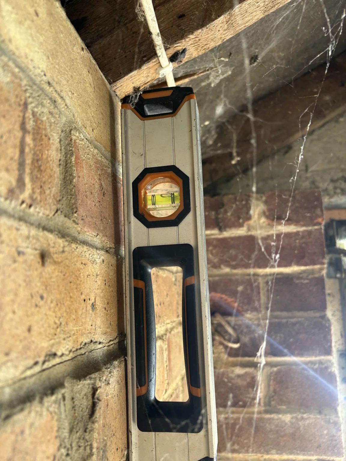 Spirit level against the inner face of a bowing single-skin garage wall