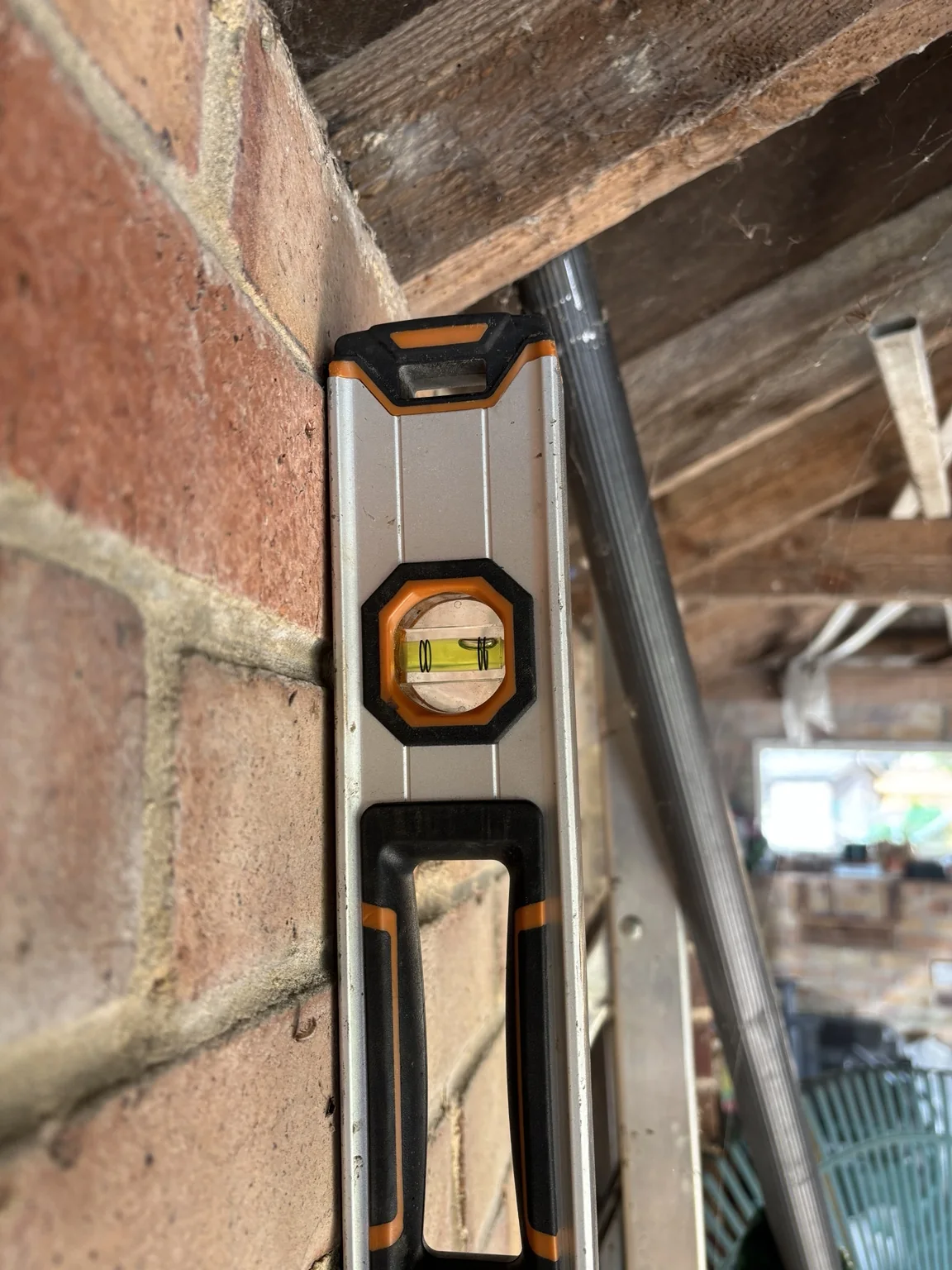 Internal view of a garage wall checked with a spirit level beneath the timber roof structure