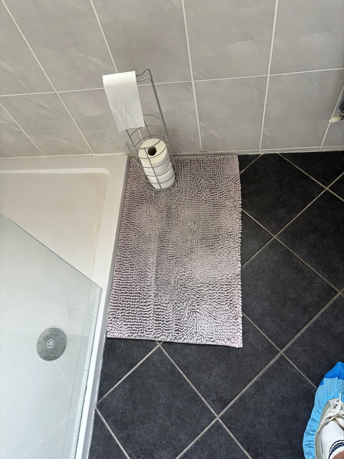 Bath mat concealing damaged bathroom floor tiles