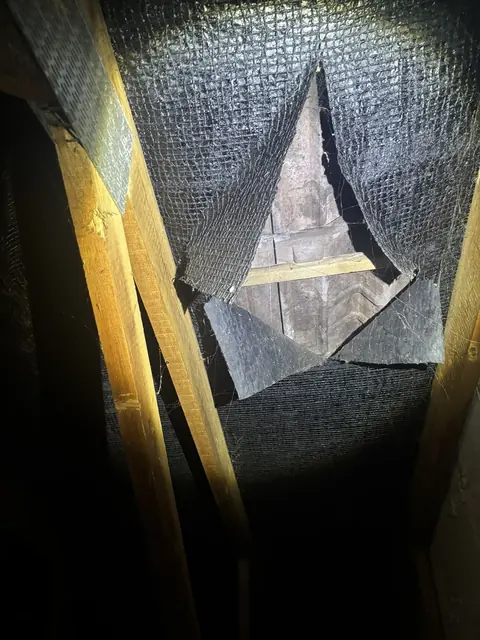Torn secondary roof lining within a 1970s roof space