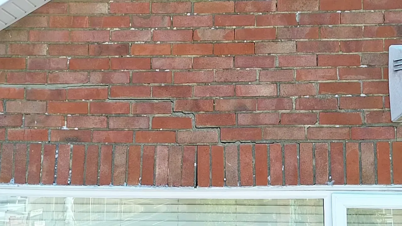 Stepped cracking to brickwork above a first-floor window opening on a 1970s detached house in Waterlooville